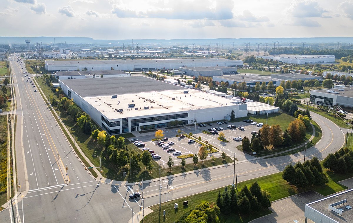 Aerial view of QRC Logistics' Toronto 3PL warehouse near Pearson Airport, featuring a spacious facility, parking lot, and surrounding greenery, emphasizing logistics and distribution capabilities.