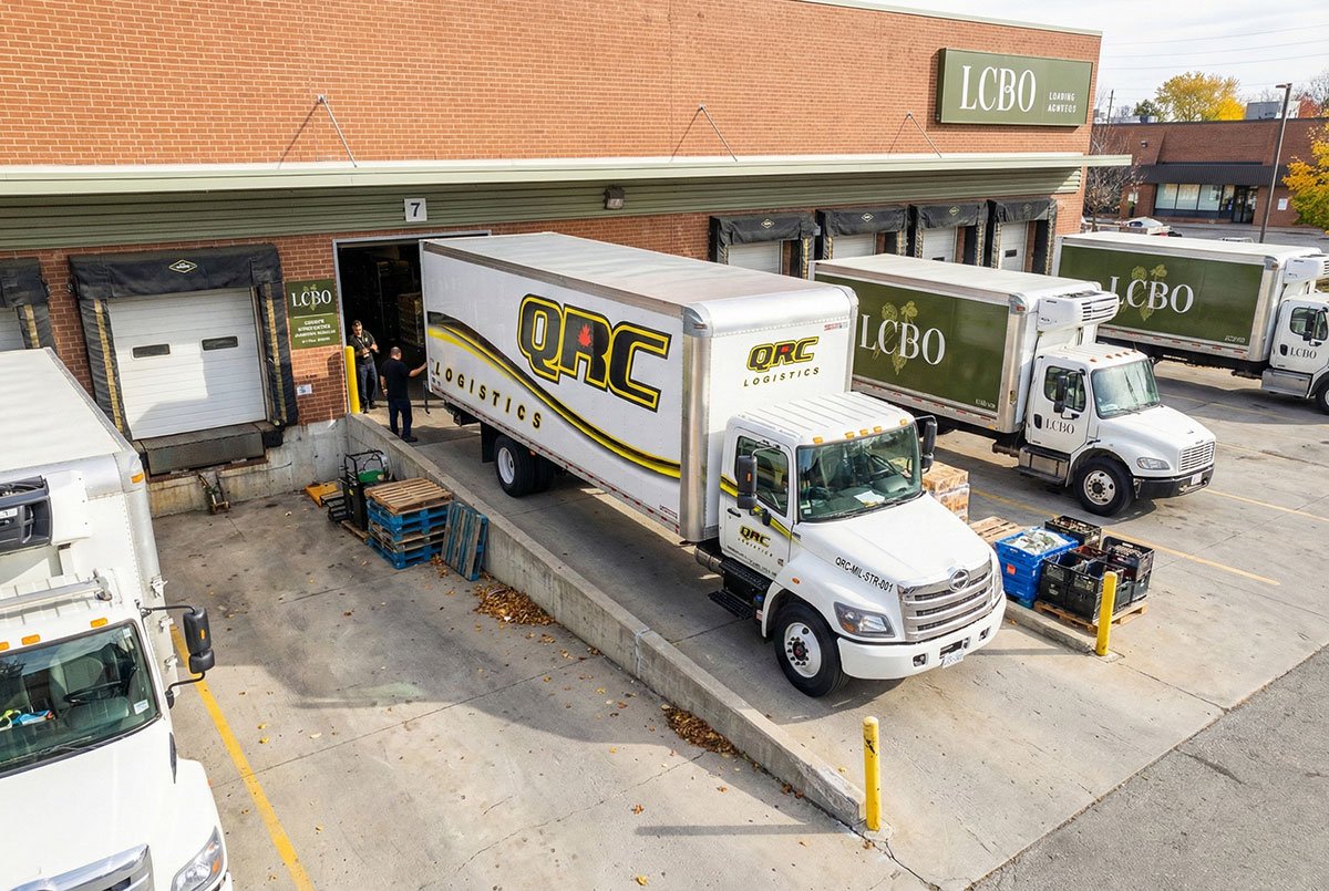 QRC Logistics truck at an LCBO loading dock handling craft beer distribution deliveries with pallets staged outside the warehouse.