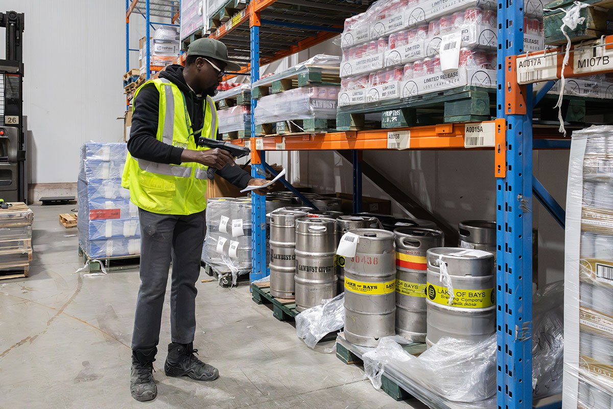 QRC Logistics warehouse associate scanning kegs and palletized cases to ensure craft beer inventory accuracy on racked storage shelves.