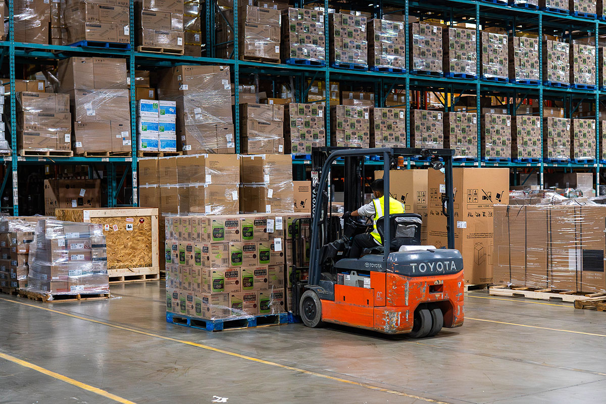 Forklift operator transporting a wrapped pallet of boxes in a modern Toronto logistics warehouse, highlighting efficient 3PL services for freight forwarders in Canada.