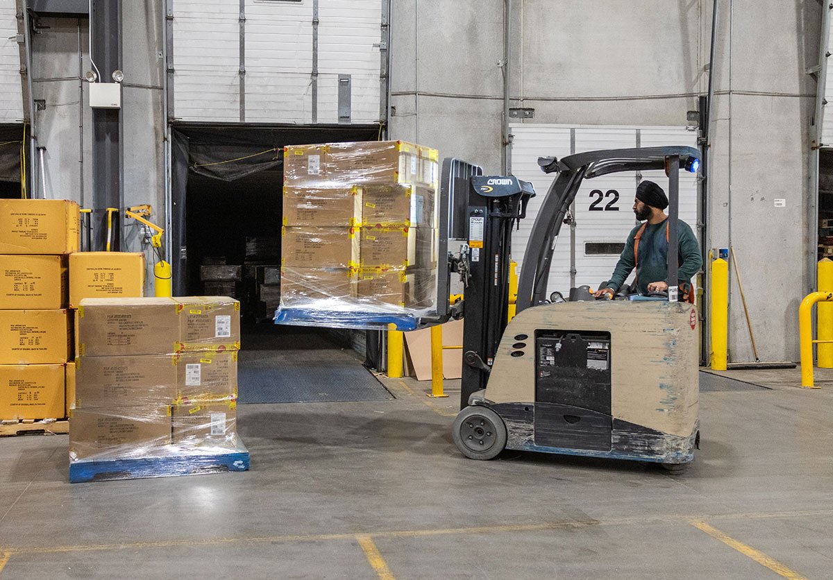 Forklift operator moving wrapped skids at a warehouse loading dock, representing QRC Logistics local cartage and per skid LTL delivery in Southern Ontario. Forklift operator moving wrapped skids at a warehouse loading dock, representing QRC Logistics local cartage and per skid LTL delivery in Southern Ontario.