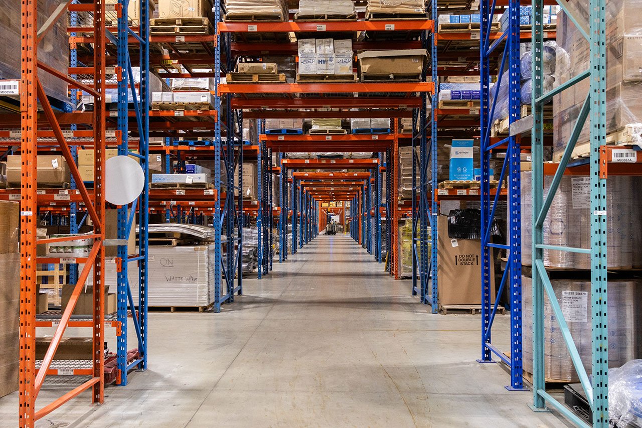 Warehouse aisle with tall pallet racks stocked with boxed inventory Warehouse aisle with tall pallet racks stocked with boxed inventory