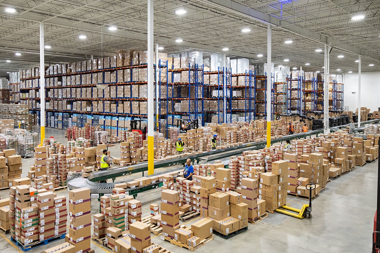 Warehouse workers processing boxed inventory around conveyors and pallet storage racks Warehouse workers processing boxed inventory around conveyors and pallet storage racks